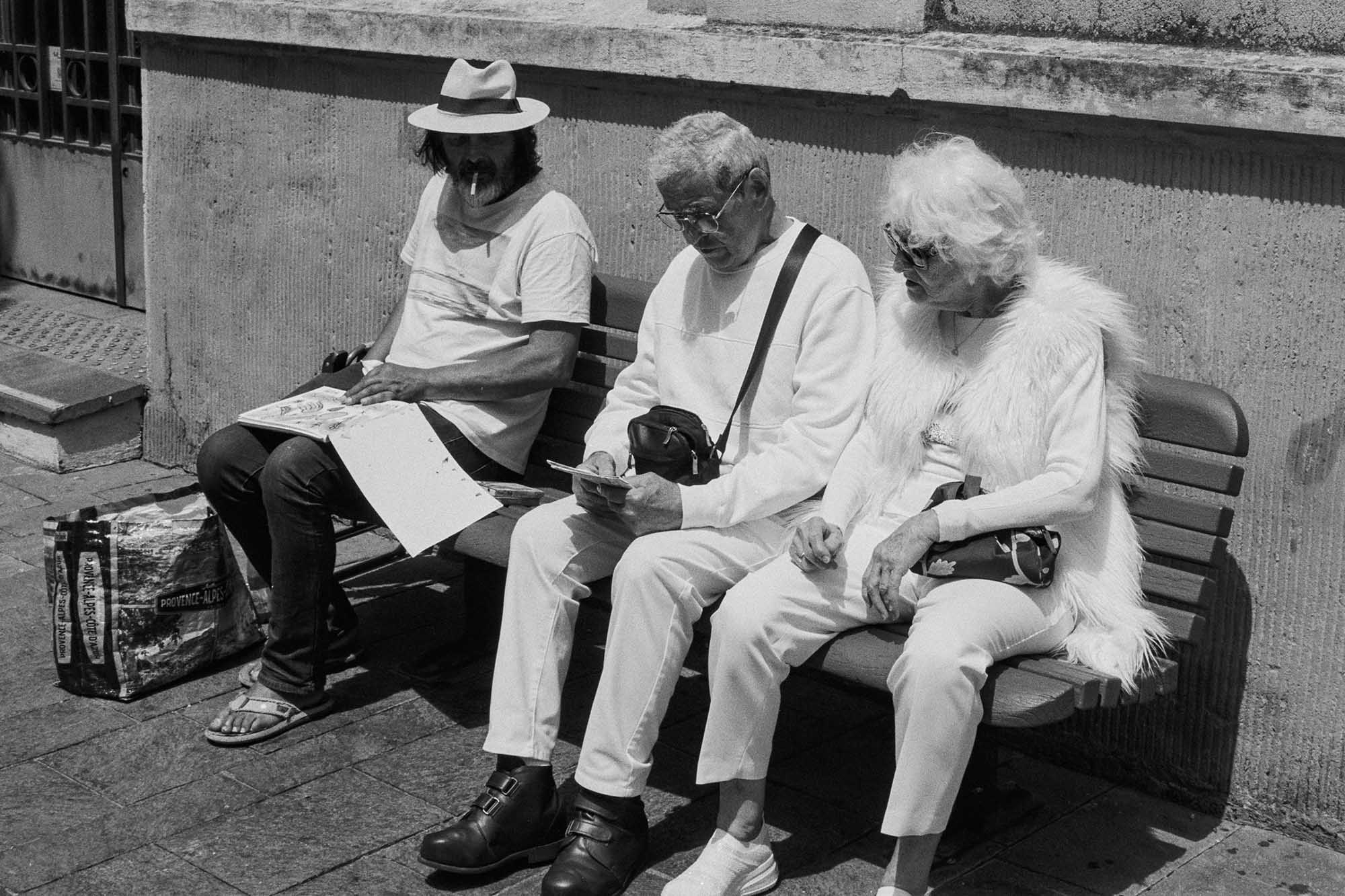 Three people sat on a bench in Cannes.