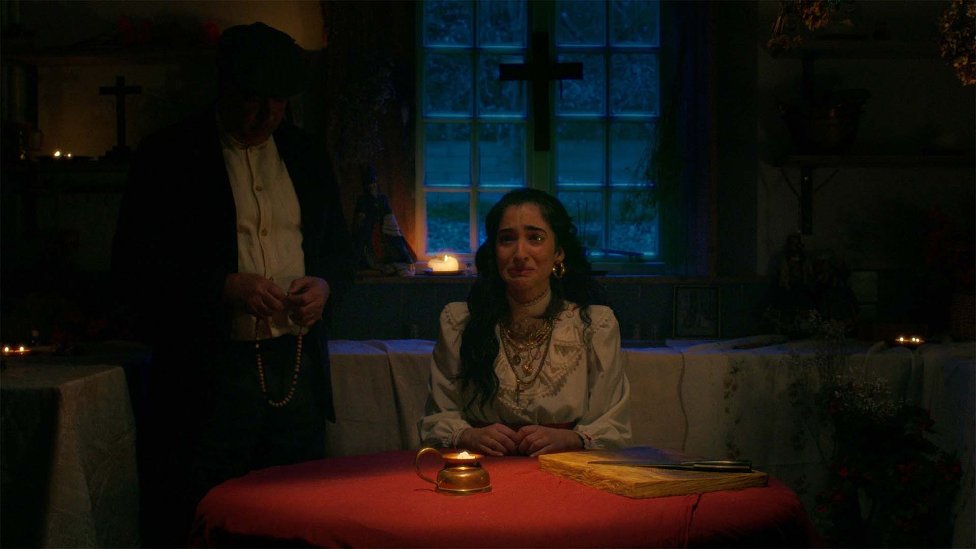 Woman sat at a dining table surrounded by an ominous atmosphere.